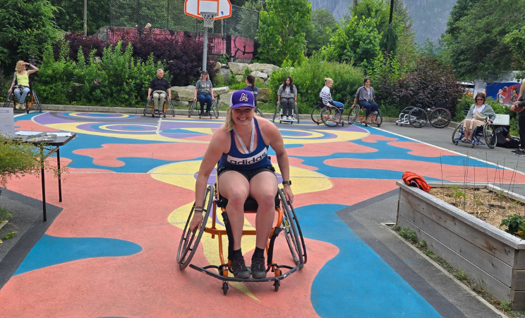 Women sits in a wheelchair in front of Basketball court